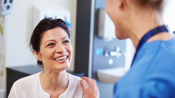 Woman smiling at person in nurse uniform