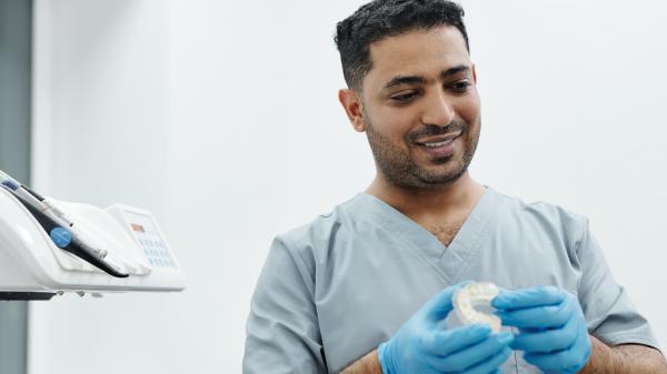 A man in scrubs looks contentedly at something in his gloved hands