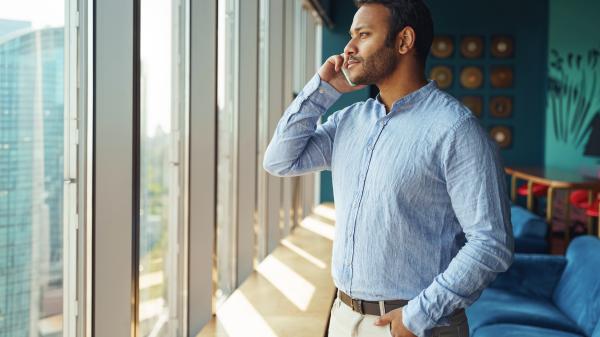 Looking out a window, a man speaks on his mobile phone