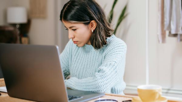 A woman works at her desk behind her laptop