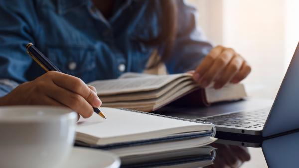 Books sit on a desk in front of an individual