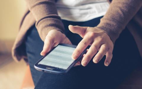 Woman's hands use phone on lap