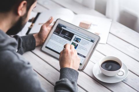 A man scrolls on his tablet
