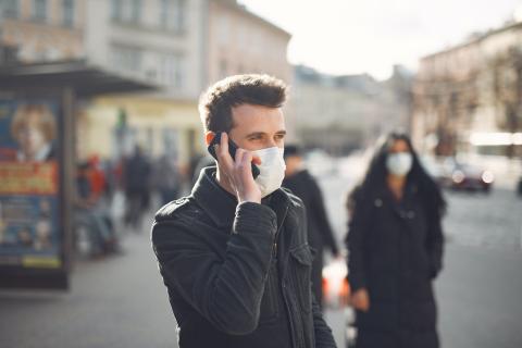 Man with mask talks on mobile phone in the street