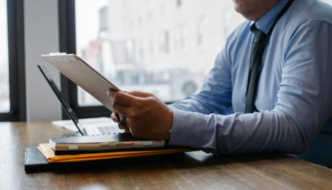A man in business attire studies papers in front of him