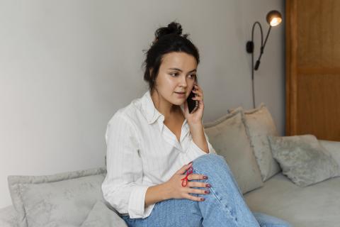 A young woman talks on the phone while staring into the distance