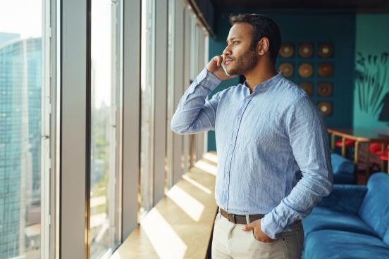 Looking out a window, a man speaks on his mobile phone